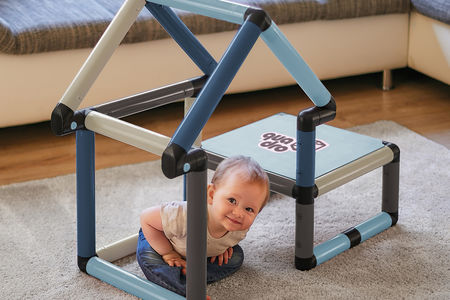 Child sitting inside a playhouse and climbing frame